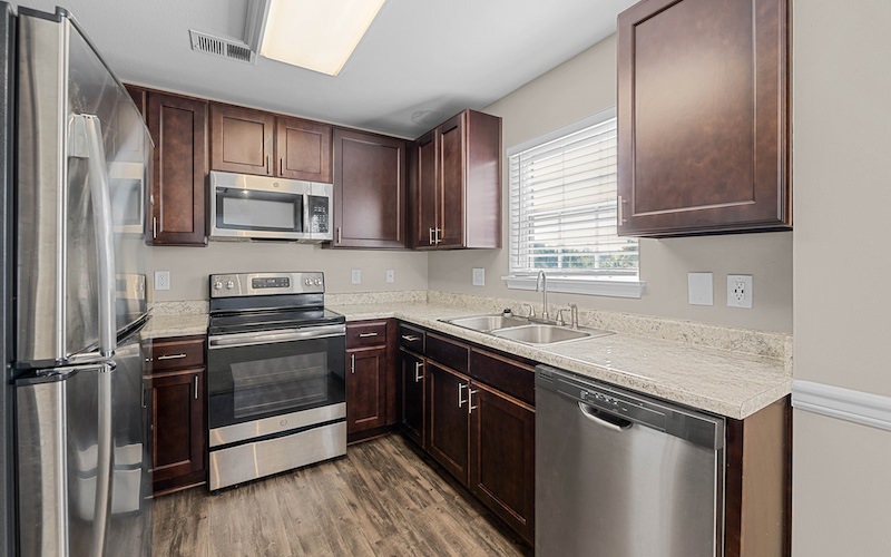 Spacious and well lit kitchen with wood floors and stainless steel appliances with access to the living room 